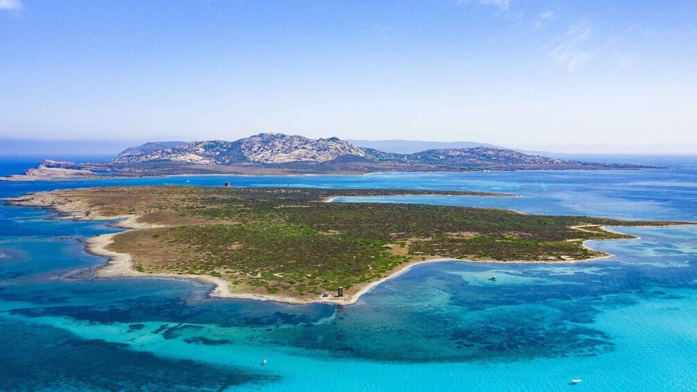 An aerial view of a coastal island with clear blue waters, surrounded by mountains. 2