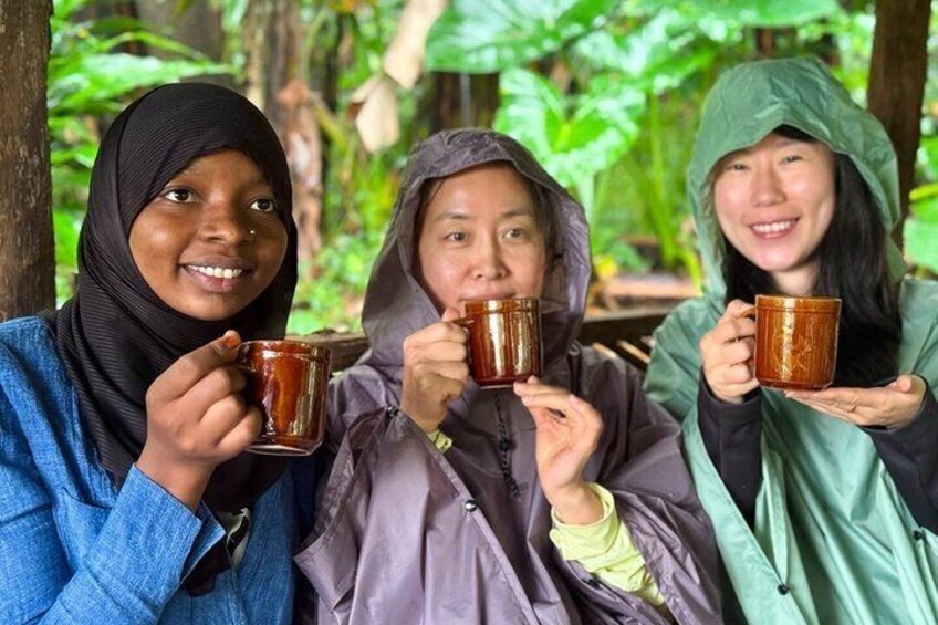 Three individuals holding mugs in a forested area. 5