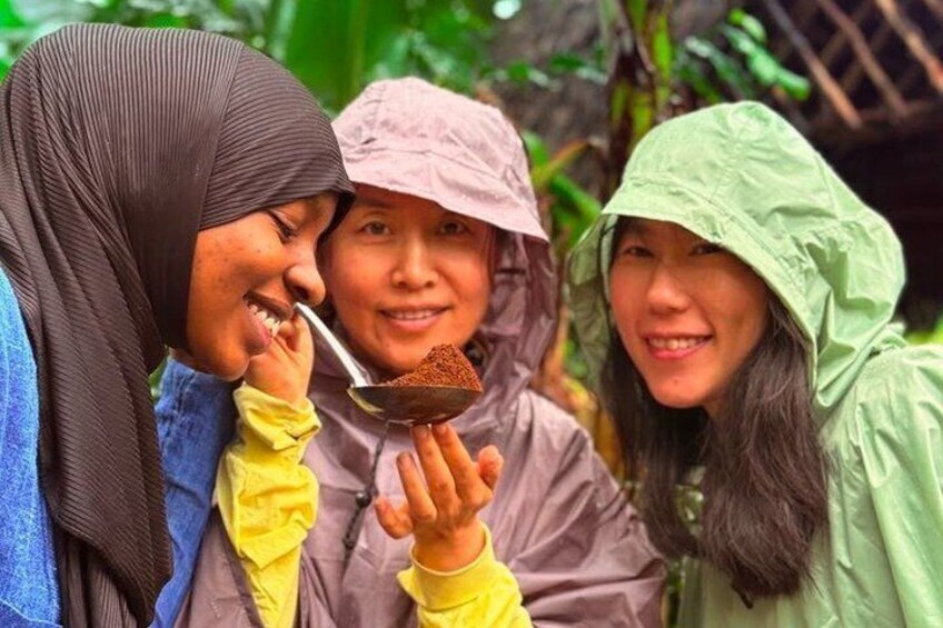 Three people outdoors, one holding a spoon with a brown substance. 4