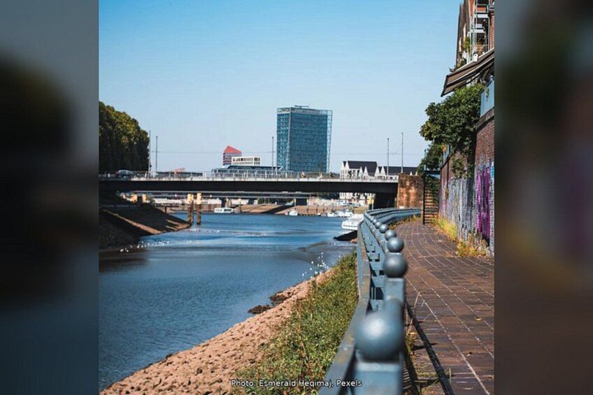 A river with a bridge, a modern building, and a walkway with graffiti. 2