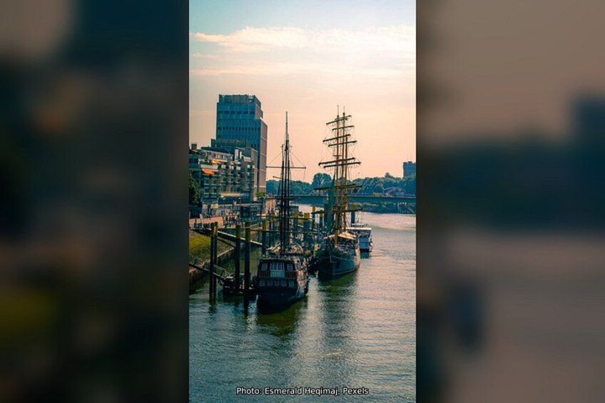 A harbor with a tall ship docked, buildings in the background, and a bridge. 3