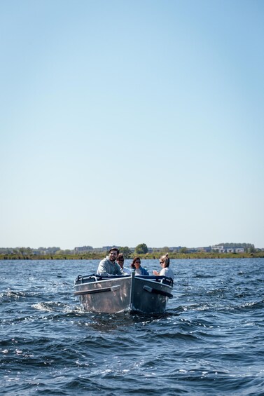 A small boat with four people on a calm body of water. 2