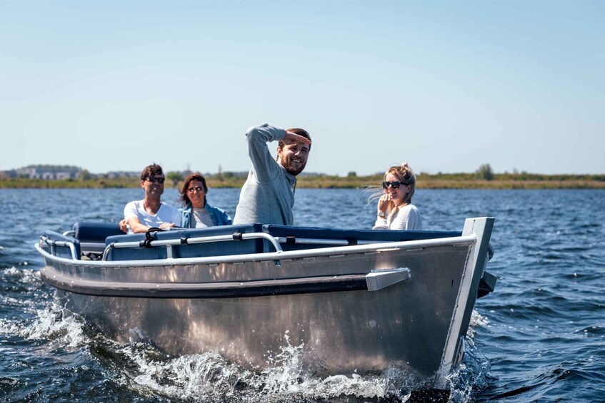 A small motorboat on calm water with four people aboard. 5