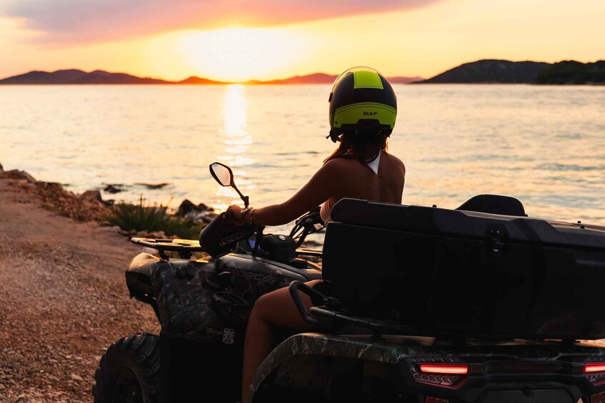A person riding an ATV on a beach at sunset. 2