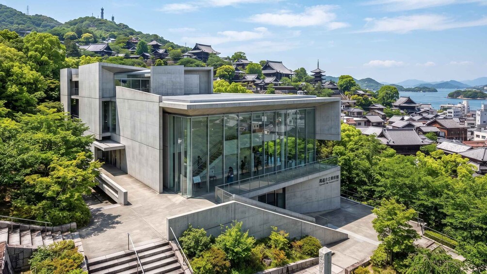 A modern building with glass windows and concrete structures, surrounded by lush greenery and traditional Japanese architecture in the background. 5