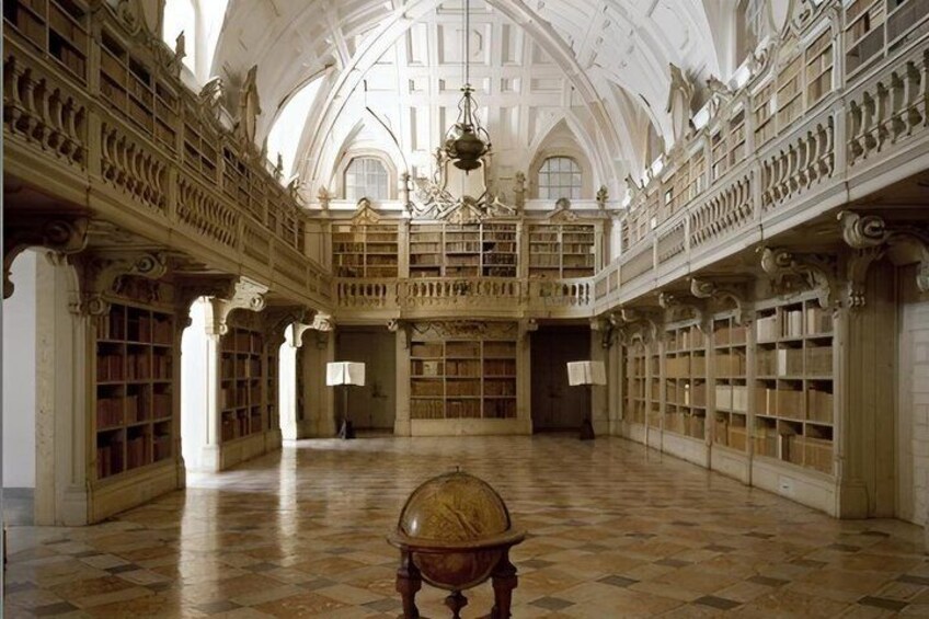 An ornate library interior with high ceilings, detailed woodwork, and a large chandelier. 5