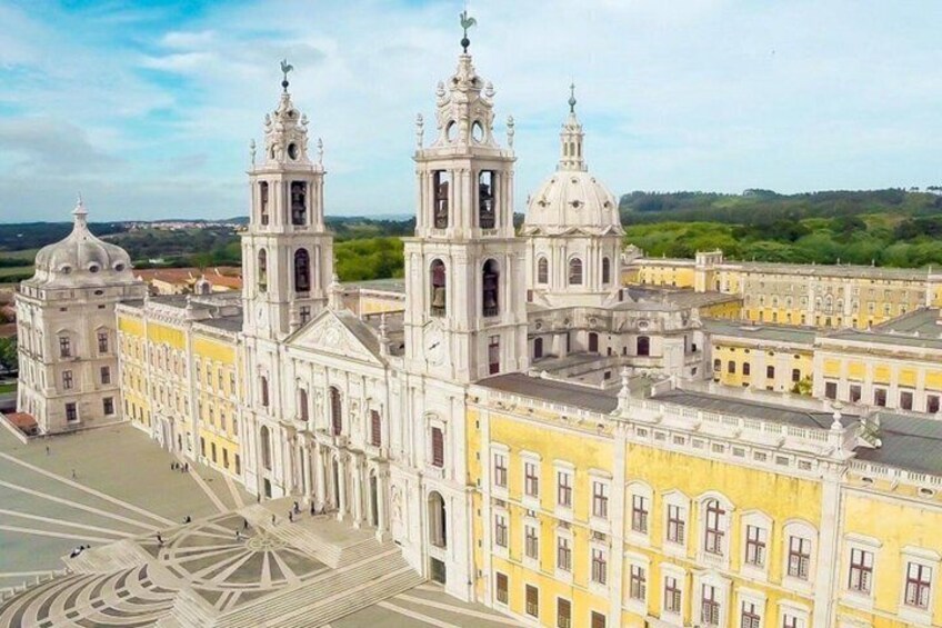 A large white cathedral with two towers and a dome, surrounded by yellow buildings. 3