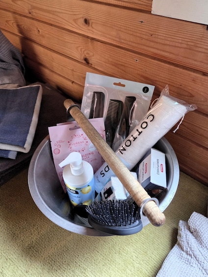 A metal bowl containing hair care items like combs, a brush, and a bottle of shampoo. 2