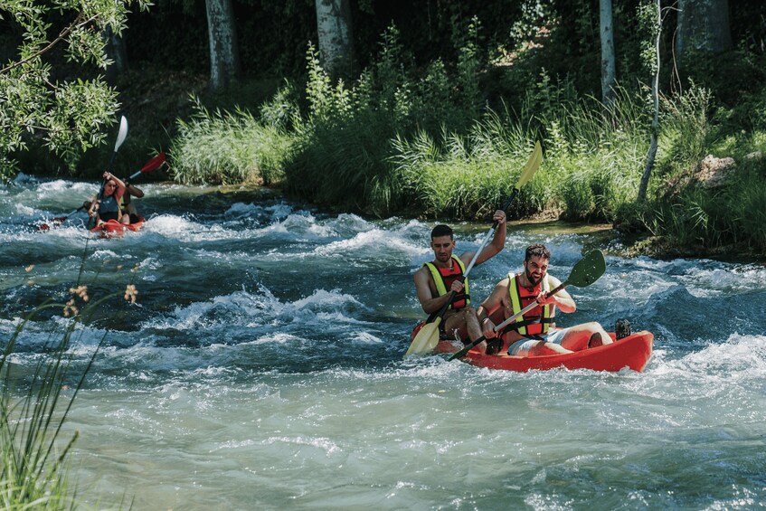 People kayaking on a river surrounded by greenery. 1