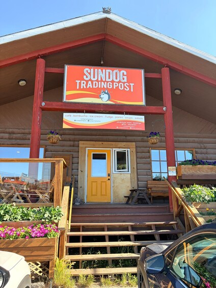 A wooden building with a sign reading 'Sundog Trading Post.' 3