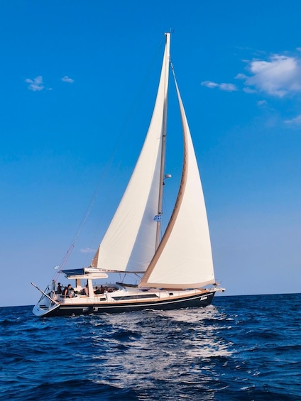 A sailboat with white sails on a blue sea under a clear sky. 1