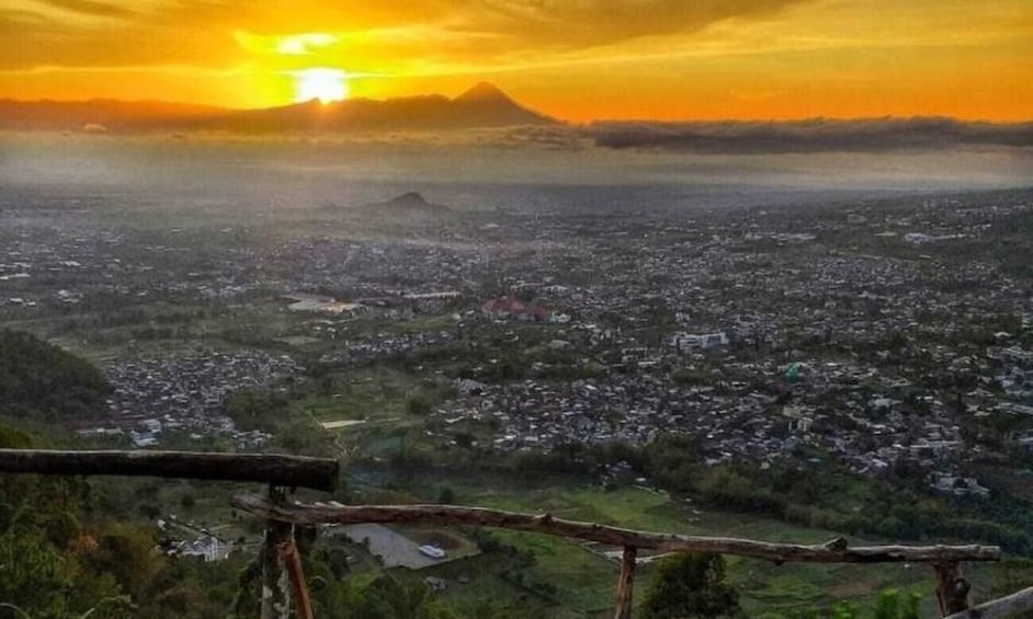 A cityscape at sunset with a mountain in the background. 1