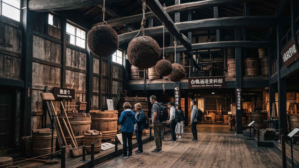 A museum interior with wooden barrels, hanging fermentation vats, and visitors exploring exhibits. 4
