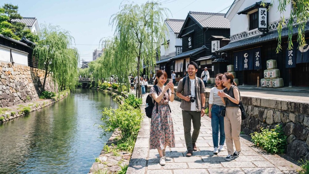 A group of people walking along a riverside path in a traditional Japanese town. 3