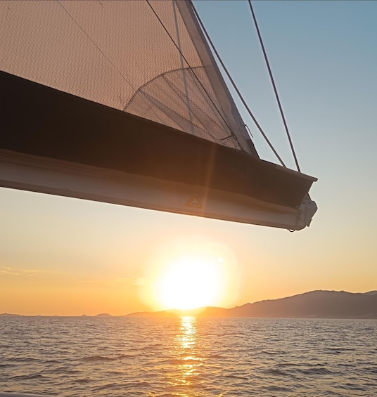 A sailboat with a sun reflecting off the water during sunset. 3