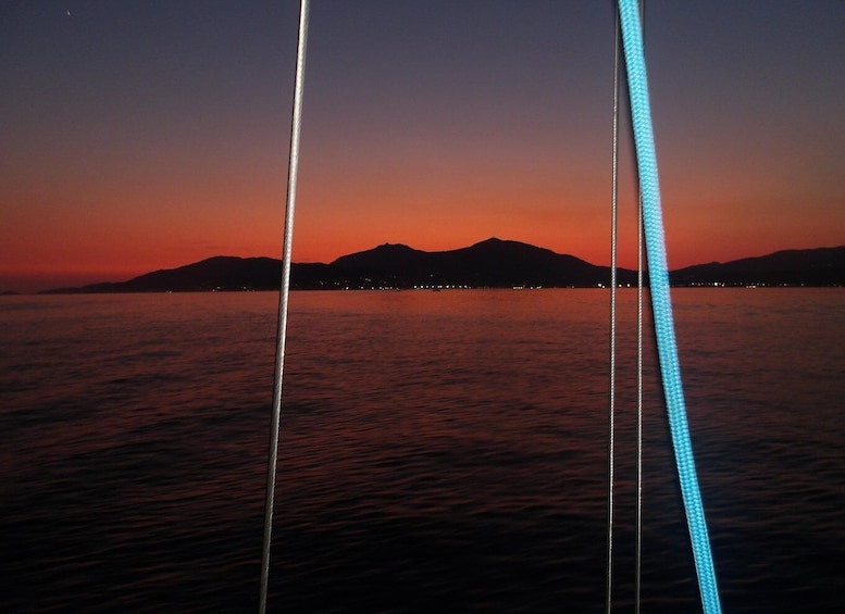 A sunset over a body of water with mountains in the distance and a cable car track in the foreground. 1