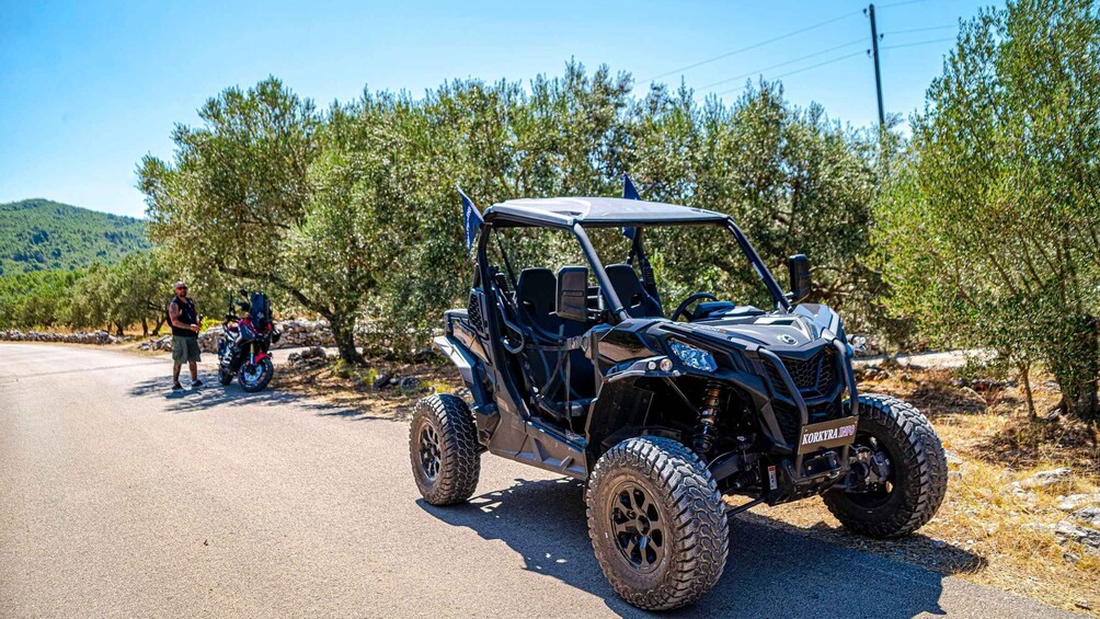 A black off-road vehicle parked on a road with a person standing beside it. 4