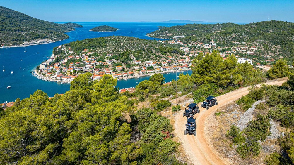 A coastal town with a marina, surrounded by hills and dense greenery. 1