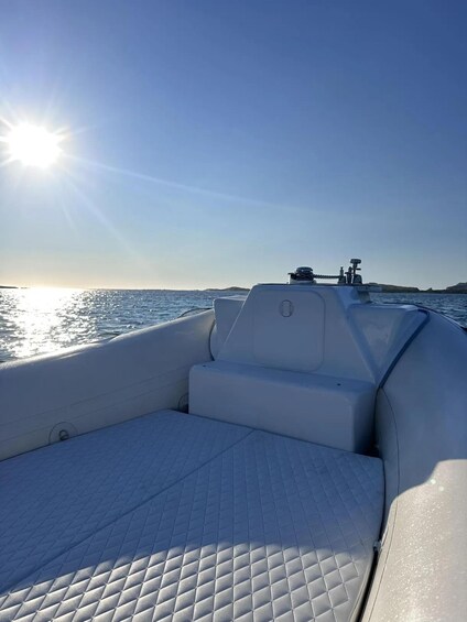 A boat's interior with a quilted floor and a view of the water and distant land under a clear sky. 3