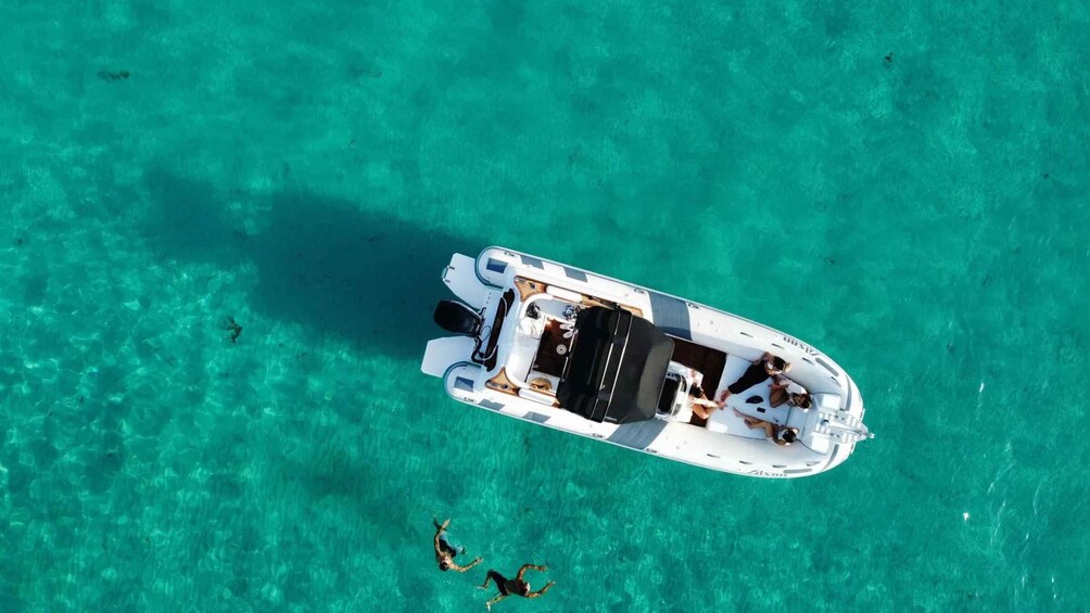 A white boat with a motor and seating, floating on clear turquoise water. 4