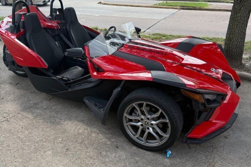 A red sports car with black accents parked on a concrete surface. 4