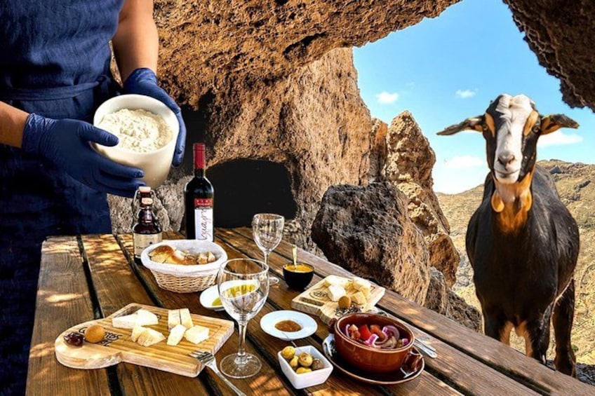 A table with food and wine, a goat, and a rocky landscape. 1
