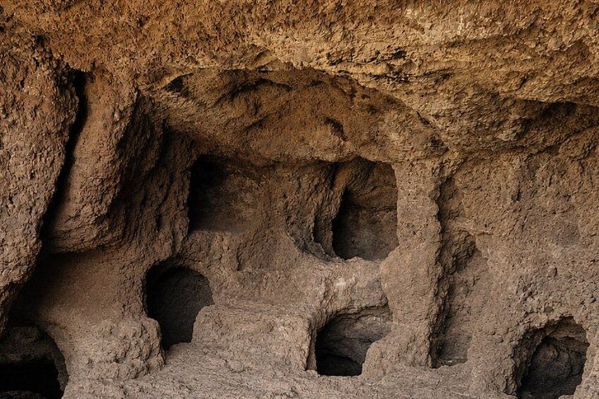 A cave with multiple small openings and a rough, textured wall. 3