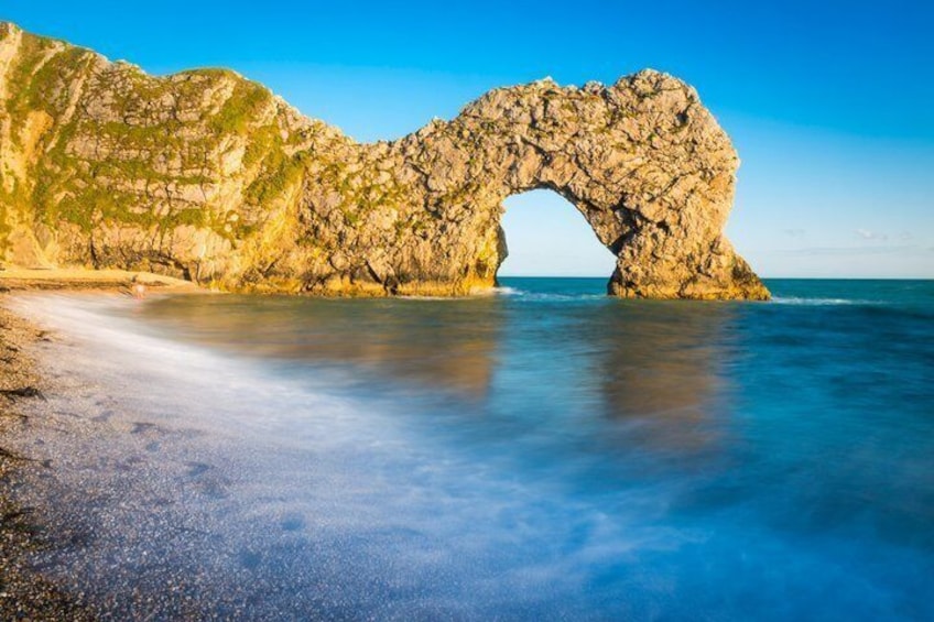 A natural rock arch formation by the sea with clear skies. 3