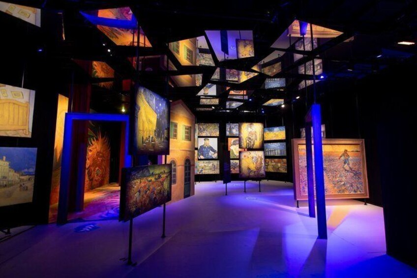 An art gallery with paintings displayed on walls and hanging from the ceiling. 1