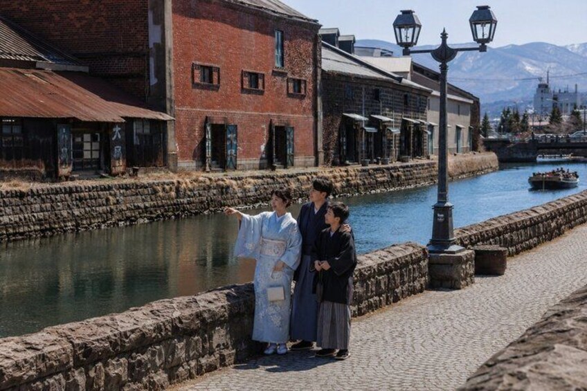 A traditional Japanese scene with a river, stone wall, and buildings. 1