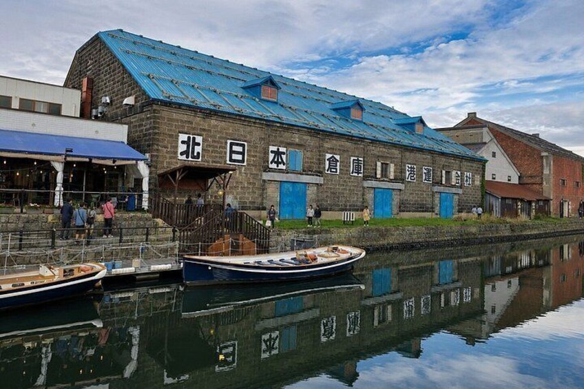 A traditional Japanese building with a blue roof, a stone facade, and a reflection in the water. 3