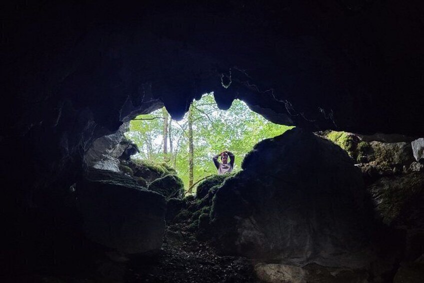 A cave entrance with a view of a forested area outside. 1