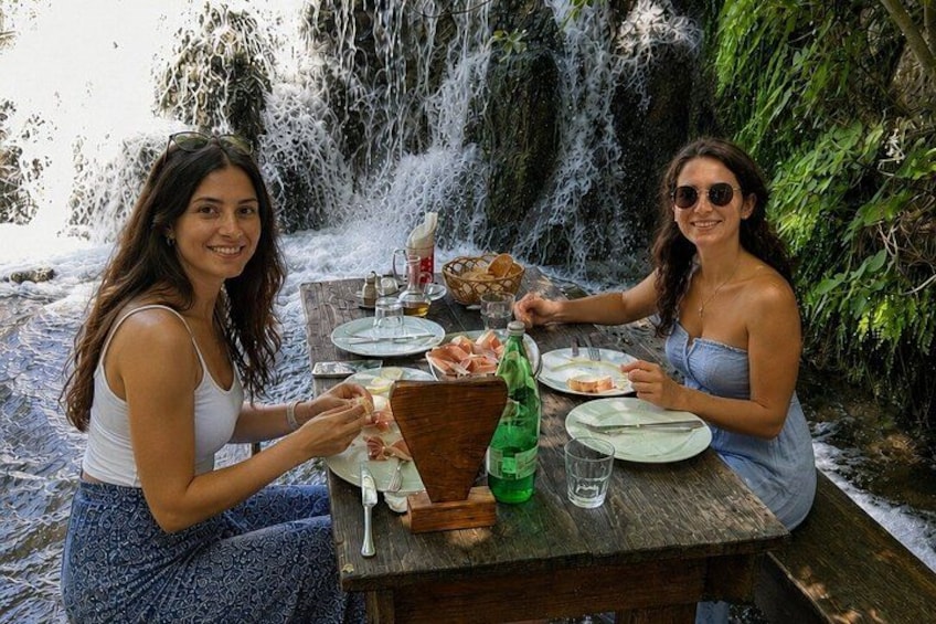 Two people dining at a wooden table by a waterfall. 4