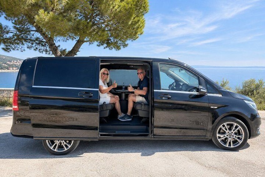 A black van parked on a road with a clear sky and a tree in the background. 5