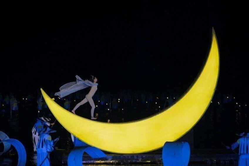 A person balancing on a large crescent moon structure. 2