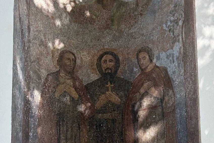 A fresco with three figures, one central and two on either side, in a religious or historical setting. 2