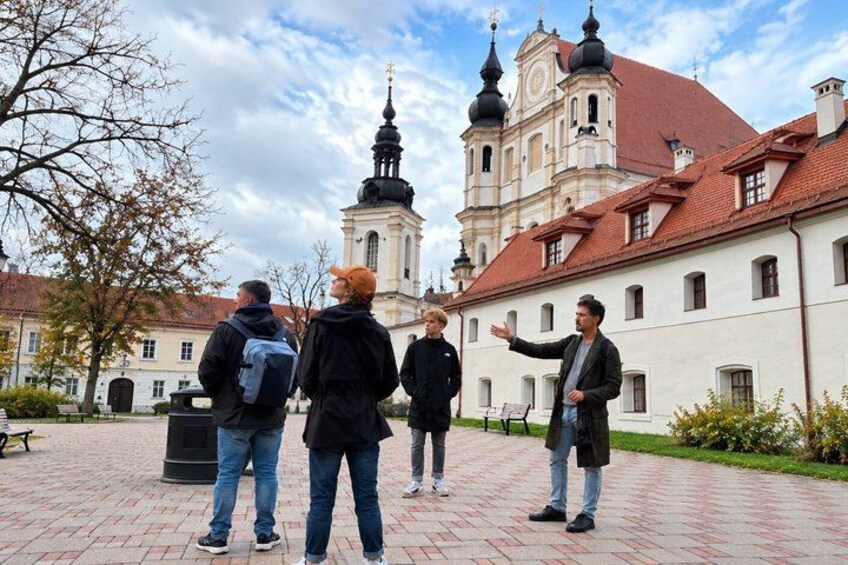 A group of people standing in a courtyard with a historic building in the background. 1