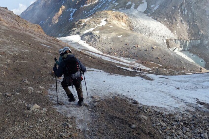 A hiker with trekking poles walking on a rocky path. 2