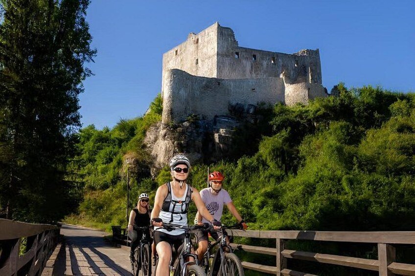 Cyclists on a bridge with a historic castle in the background. 1