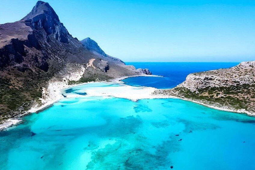 A coastal landscape with a mountain, a bay, and clear blue waters. 1