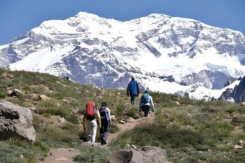 Hikers on a mountain trail with snow-capped peaks in the background. 3