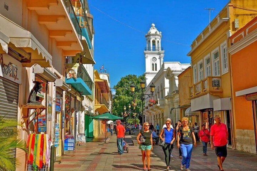 A bustling street with shops, a clock tower, and pedestrians. 4