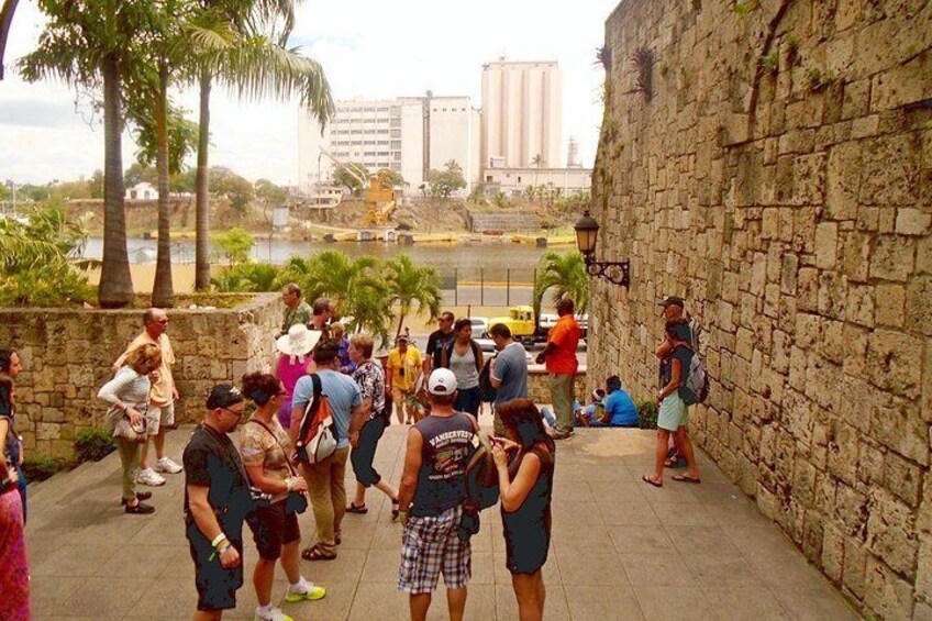 A group of people standing on a stone wall overlooking a river, with buildings in the background. 5
