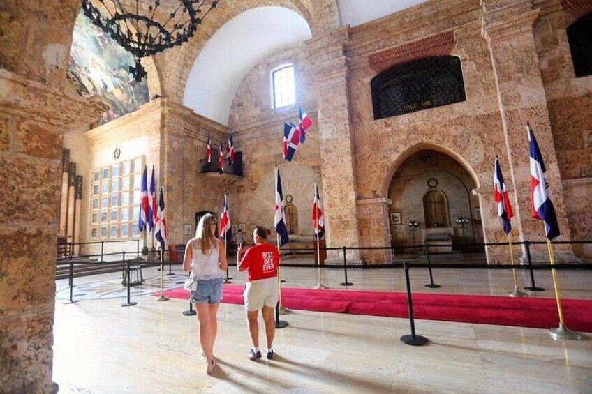 A historic building with stone walls, a red carpet, and multiple flags. 2