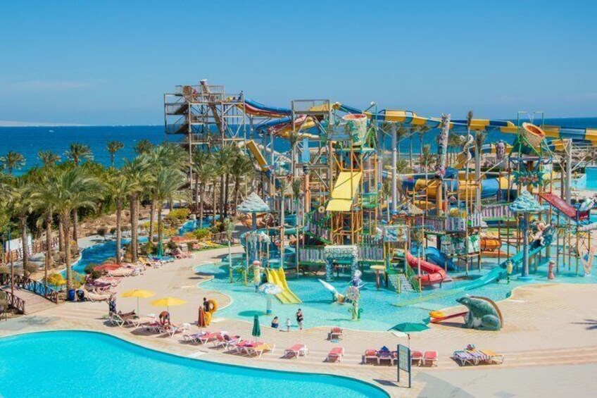A water park with slides and pools, palm trees, and a beach. 5