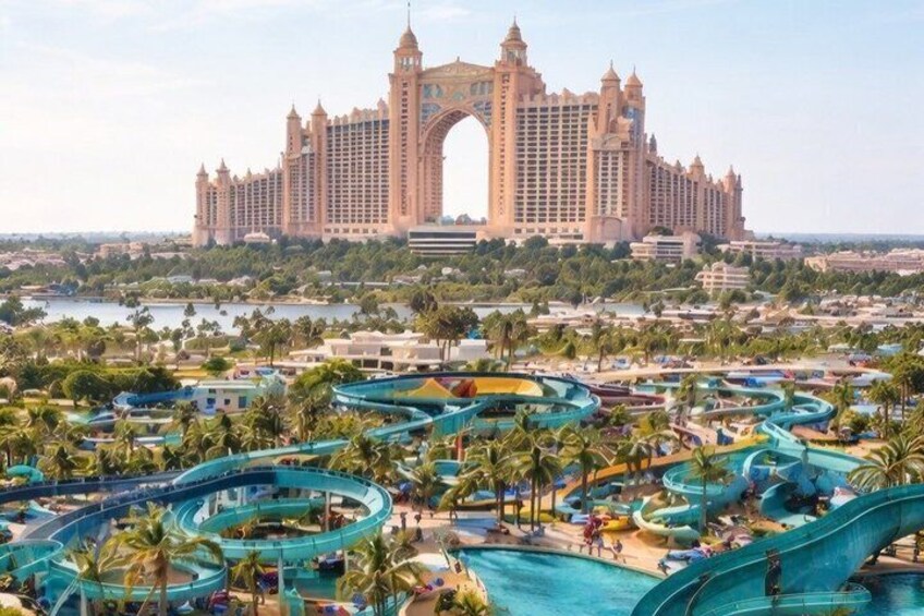A large resort with a water park, palm trees, and a grand hotel in the background. 1