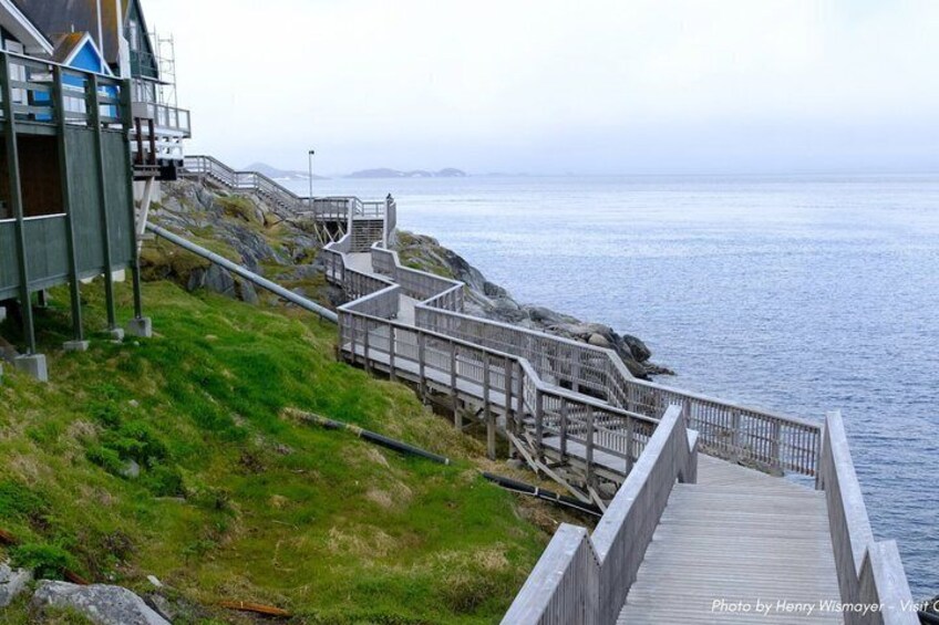 A coastal walkway with a wooden deck leading to a rocky shoreline. 5