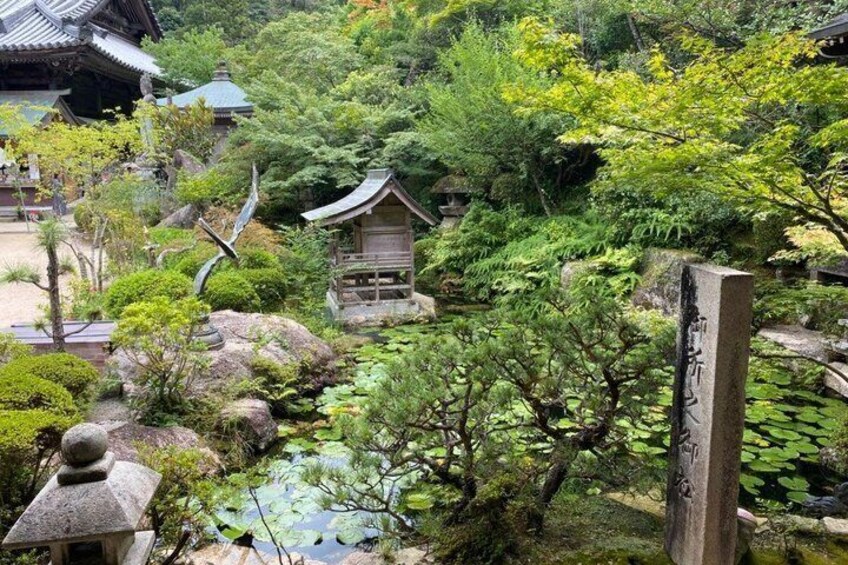 A traditional Japanese garden with a pond, rocks, and a wooden structure. 4