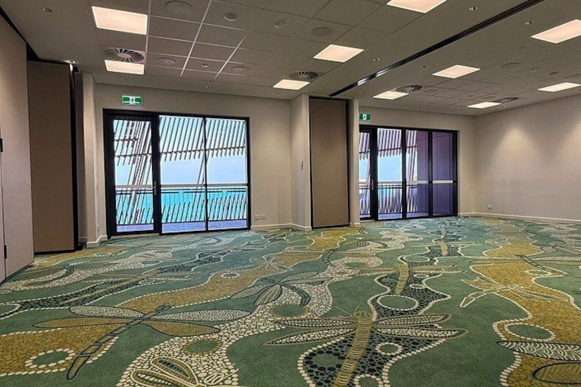 A conference room with patterned carpet, large windows, and a door. 5