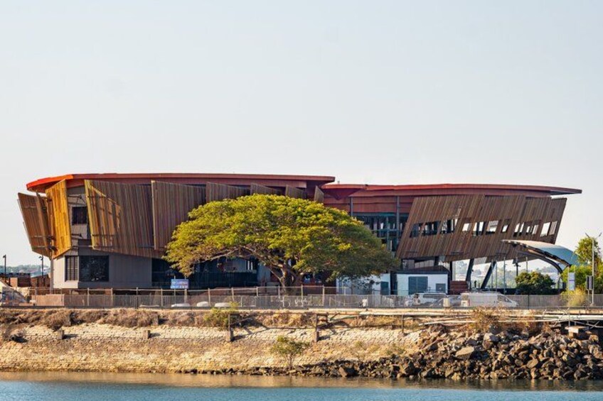 A modern building with a curved roof and a tree in front. 3